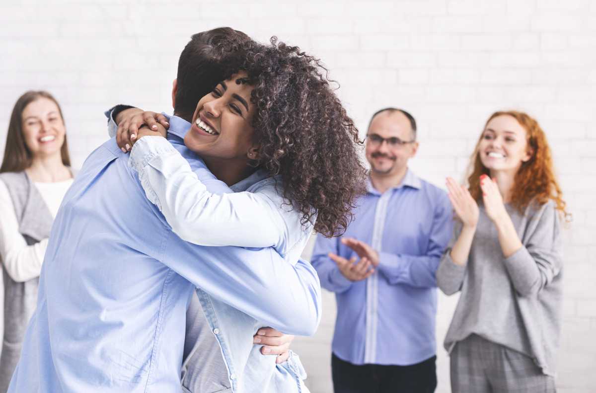 diverse-people-hugging-after-successful-workshop